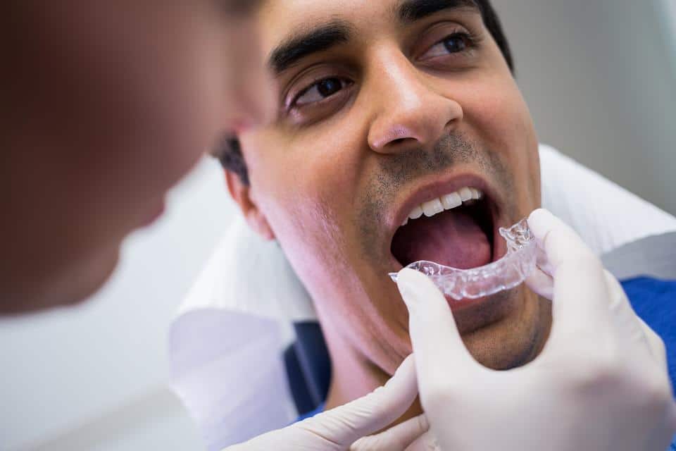 dentist-assisting-male-wear-invisible-mouthguards Performance, Comfort, and Material Mastery: The Structural Physics of Custom Athletic Mouthguards